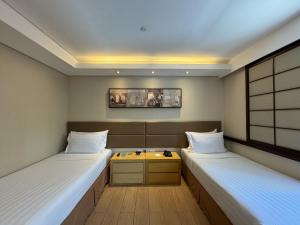 a room with two beds and a table in it at Jinjiang Inn - Makati in Manila