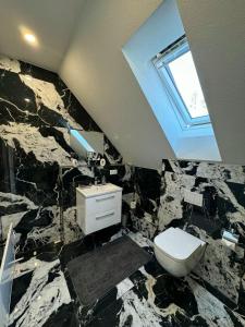 a bathroom with a stone wall with a toilet and a window at Glück Apartments (Europa-Park Rust) in Kappel-Grafenhausen