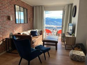 Una sala de estar con un sofá y una pared de ladrillos. en Appartement avec vue imprenable et tout le confort, en Font-Romeu-Odeillo-Via