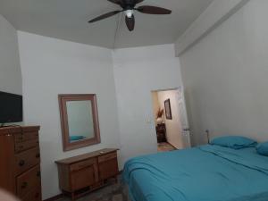 a bedroom with a blue bed and a ceiling fan at Bonito Departamento Amueblado y se factura in Guaymas