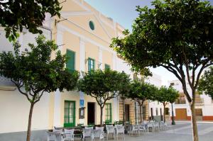a building with chairs and trees in front of it at Hostal Sixto in Rota
