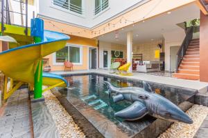 乔木提恩海滩99 Pool Villa的房子里的游泳池配有滑梯，水里还有一只海豚