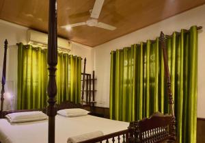 a bedroom with green curtains and a bed in a room at Reds Residency - Homestay in Cochin +240 photos