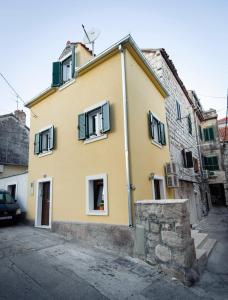 a yellow house with green shutters on a street at La Perla Luxury Apartments in Split