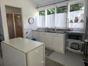 a white kitchen with a sink and a microwave at La Petite Ferme Studio Kerikeri in Kerikeri