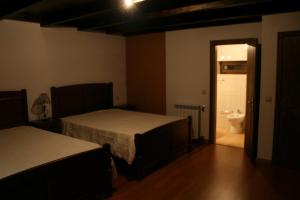 a room with two beds and a bathroom with a toilet at Abrigo de Montanha in Montalegre
