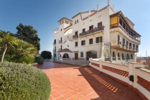 a large white building with a red brick courtyard at Arenyslux in Arenys de Mar