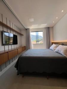 a bedroom with a large bed and a television at Apto lindo nas montanhas! in Venda Nova do Imigrante