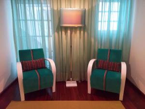 two green chairs sitting in front of a window at Monsanto GeoHotel Escola in Monsanto