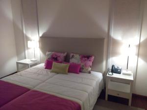 a bedroom with a large bed with pink pillows at Monsanto GeoHotel Escola in Monsanto