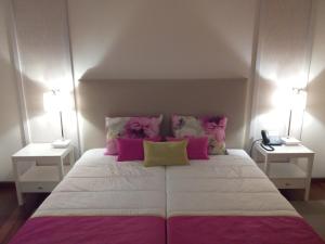 a bedroom with a large bed with pink and white pillows at Monsanto GeoHotel Escola in Monsanto
