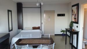 1 dormitorio con 1 cama, mesa y sillas en Studio Playa Varesse en Mar del Plata