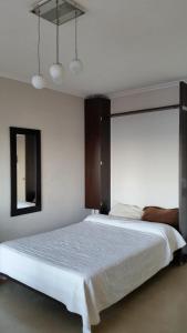 una camera da letto con un grande letto bianco e uno specchio di Studio Playa Varesse a Mar del Plata