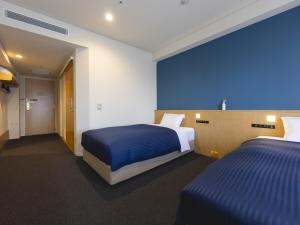 a hotel room with two beds and a blue wall at Kansai Airport Washington Hotel in Izumi-Sano