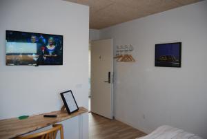 a room with a bed and a desk with a tv on the wall at Rind B&B in Herning