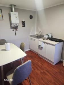 a kitchen with a sink and a table with chairs at Cabaña Full Equipada Sector Norte in Punta Arenas