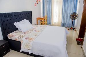 - une chambre avec un lit et un ventilateur dans l'établissement WOODLAND CENTER APARTMENTs, à Kigali