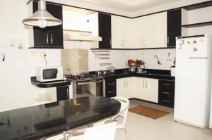 cocina con armarios blancos y nevera en blanco y negro en Casa Atalaia, en Aracaju