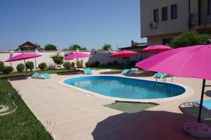 a swimming pool with pink umbrellas and chairs at Guest House Golden Flake 4km from Bolata beach in Bŭlgarevo
