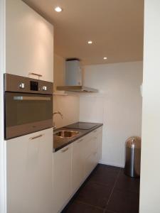 uma cozinha branca com um lavatório e um fogão em Studio Coastview em Zandvoort