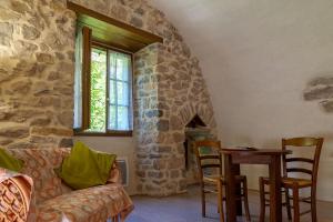 a living room with a couch and a stone fireplace at Le moulin à la caze in Veyreau