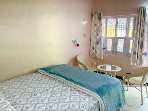a bedroom with a bed and a table and a window at Kalyan Guesthouse in Hampi