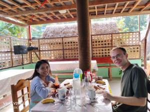 a man and a woman sitting at a table at LHOYJEAN Garden Hostel in Batuan