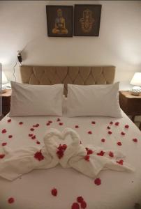 a bed with a white blanket with red flowers on it at Suíte Sol do Gostoso in São Miguel do Gostoso