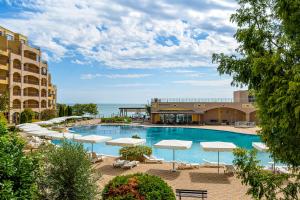 a swimming pool with white umbrellas and the ocean at Midia Holiday Apartments in Aheloy +7 photos