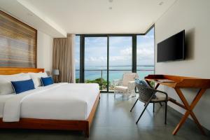 a bedroom with a bed and a desk and a television at Santos Cliff View by Nakula in Jimbaran