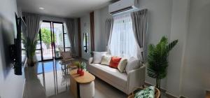 ein Wohnzimmer mit einer weißen Couch und einem Fenster in der Unterkunft Calm & Cozy Vacation House in Rawai Beach