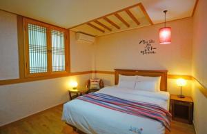 a bedroom with a bed and two tables and two windows at Gamyoungroo Hanok Hotel in Jeonju