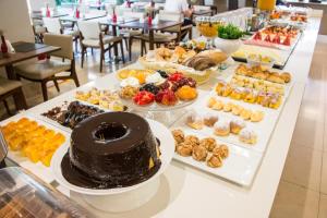 una mesa con un gran pastel de chocolate y varios pasteles en SAN MARINO SUITES HOTEL By NOBILE, en Goiânia