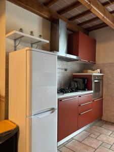 a kitchen with a white refrigerator and red cabinets at Rosso Mattone Mondovì in Mondovì