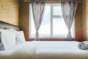 uma cama em um quarto com janela em Luxurious and Comfy 2BR at Vida View Makassar Apartment By Travelio em Pampang