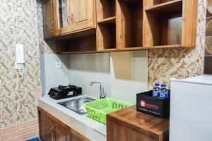 uma pequena cozinha com pia e geladeira em Luxurious and Comfy 2BR at Vida View Makassar Apartment By Travelio em Pampang