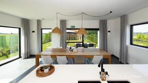 a dining room with a table and chairs and windows at Vakantiehuis Paula in Watervliet