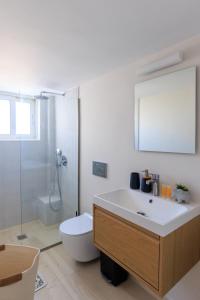 a bathroom with a sink and a toilet and a mirror at AIOLOS elegant escapes GLYFADA apartment in Athens +27 photos