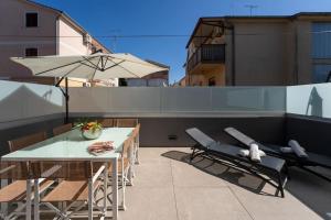 a patio with a table and chairs and an umbrella at Casa Cocooon in Funtana