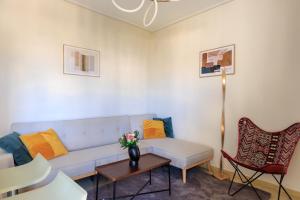 a living room with a couch and a table and chairs at AIOLOS elegant escapes GLYFADA apartment in Athens