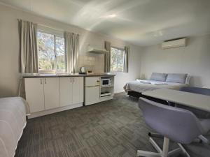 a bedroom with two beds and a desk and a kitchen at Mt Barker Holiday Park - Western Australia in Mount Barker