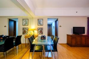 a dining room with a table and chairs and a television at Luxury 3BR Apartment at Sudirman Tower Condominium By Travelio in Jakarta