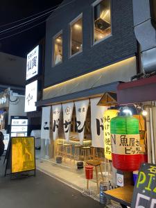 frente a una tienda con mesas y sillas frente a un edificio en Central Osaka 天神橋筋六丁目駅徒歩2分 屋上テラス付き一軒家 天満居酒屋街2分 梅田10分 難波15分, en Osaka