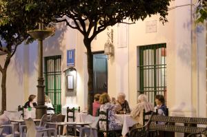 a group of people sitting at tables in front of a building at Hostal Sixto in Rota