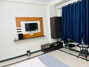 a living room with a tv and a table and chairs at New Hotel Blue Moon in Jaipur