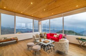 un soggiorno con ampie finestre e un divano rosso di Soul Storries - A Luxury Wellness Estate, Mussoorie a Mussoorie