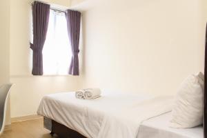 ein Schlafzimmer mit einem Bett mit zwei Handtüchern darauf in der Unterkunft Comfortable and Homey 3BR at Meikarta Apartment By Travelio in Cikarang