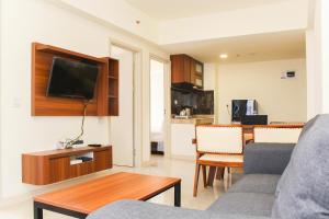 ein Wohnzimmer mit einer Couch und einem Tisch mit einem Fernseher in der Unterkunft Comfortable and Homey 3BR at Meikarta Apartment By Travelio in Cikarang