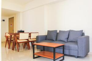 ein Wohnzimmer mit einem blauen Sofa und einem Tisch in der Unterkunft Comfortable and Homey 3BR at Meikarta Apartment By Travelio in Cikarang