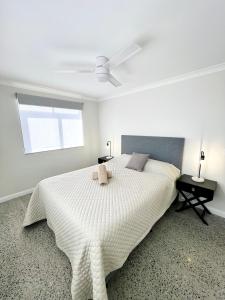 um quarto branco com uma cama grande e uma ventoinha de tecto em Sunset Beach Holiday Park em Geraldton